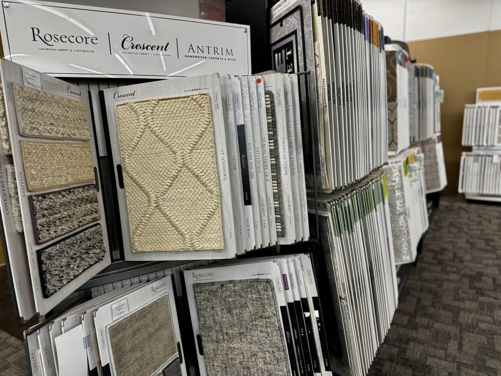 Wide variety of carpet samples on display racks in Northern Michigan Kiss Carpet showroom, including luxurious Rosecore and Crescent brands, to help choose the perfect texture and color.